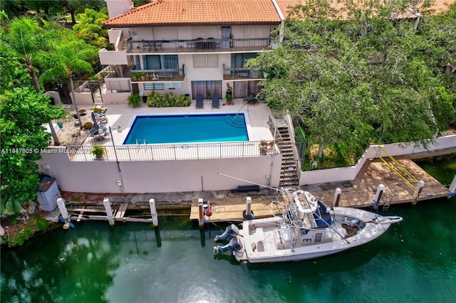 view of swimming pool with a water view, a dock, and a patio