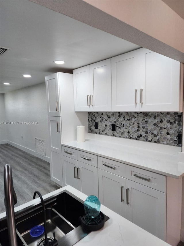 kitchen with white cabinets, tasteful backsplash, and hardwood / wood-style floors