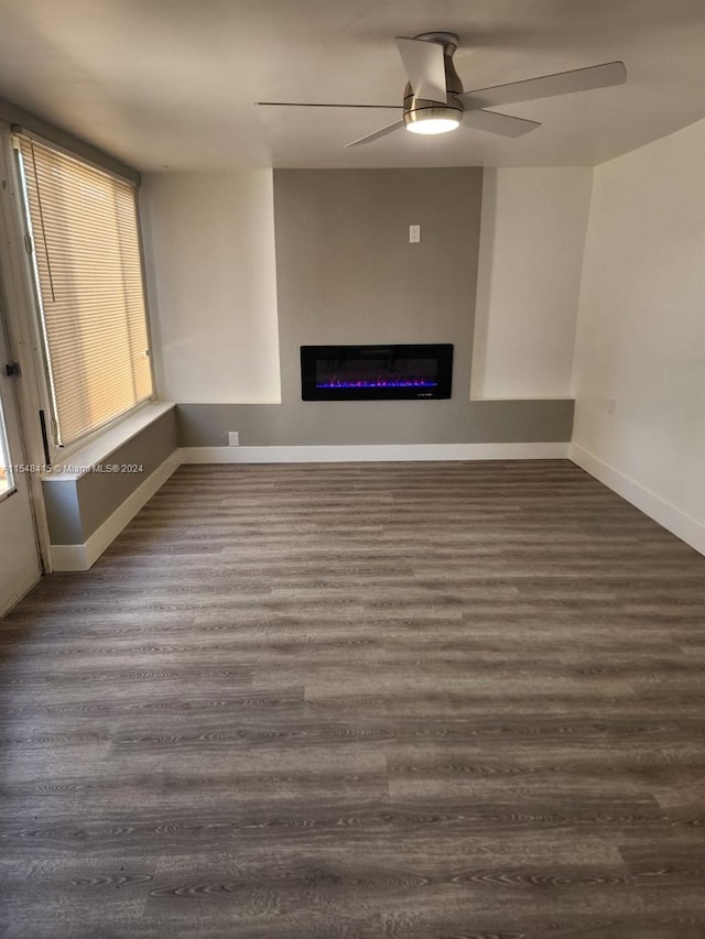 unfurnished living room featuring dark wood-type flooring and ceiling fan