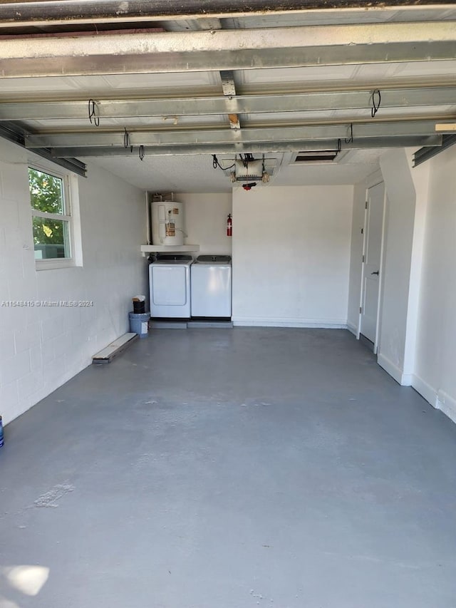 garage featuring water heater and washing machine and clothes dryer