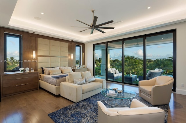 living room featuring hardwood / wood-style floors, a tray ceiling, and ceiling fan