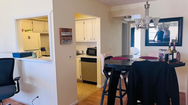 kitchen with light tile floors, white cabinets, dishwasher, an inviting chandelier, and decorative light fixtures