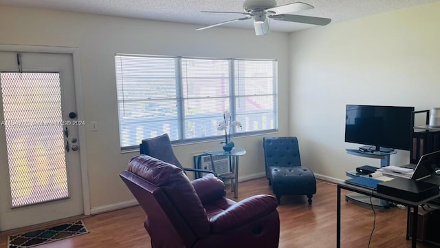 living room with a textured ceiling, ceiling fan, and wood-type flooring