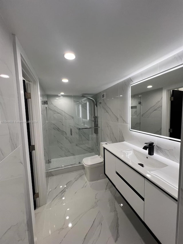 bathroom with tile walls, an enclosed shower, vanity, and toilet