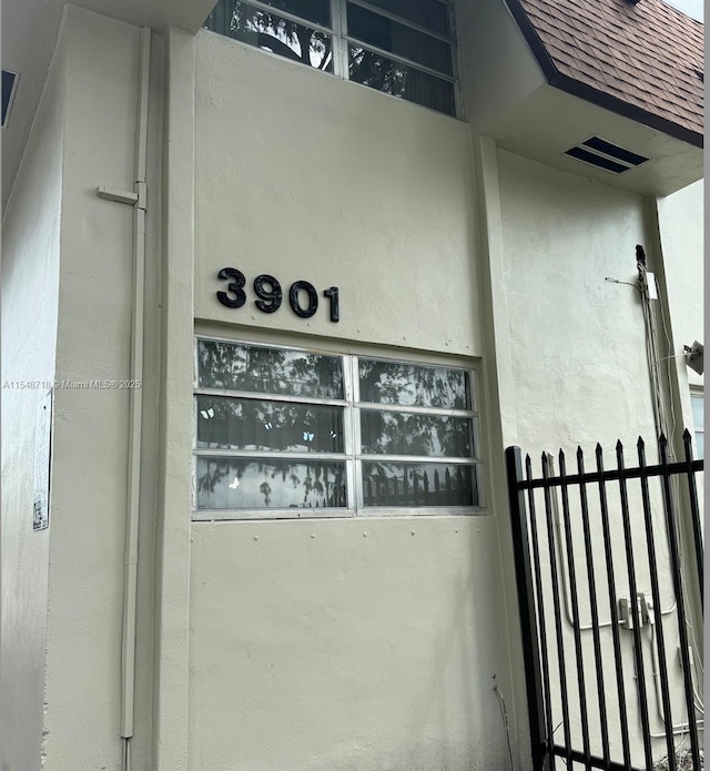 details featuring stucco siding, visible vents, and a shingled roof