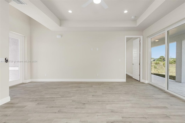 empty room with ceiling fan and a raised ceiling