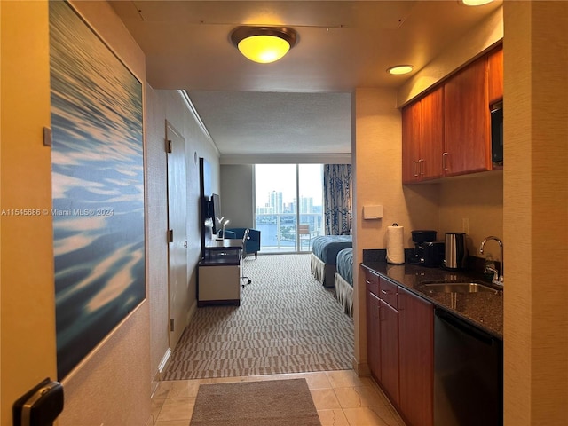 kitchen featuring dark stone counters, light colored carpet, black dishwasher, and sink