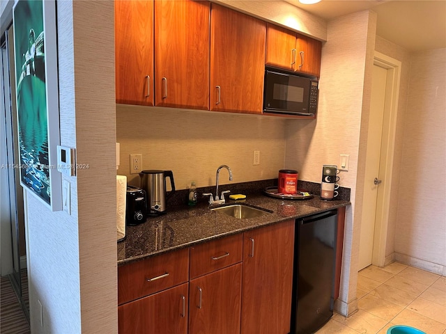 kitchen with dark stone countertops, black appliances, sink, and light tile floors