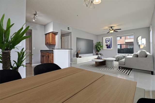 living room featuring light tile floors, track lighting, and ceiling fan with notable chandelier