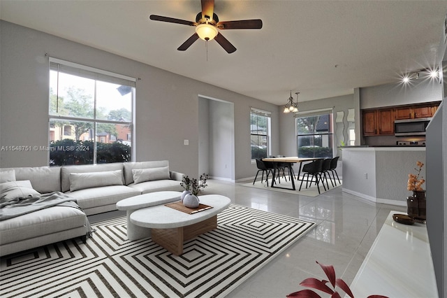 living room with light tile floors and ceiling fan with notable chandelier