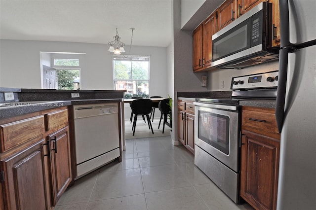 kitchen featuring a notable chandelier, appliances with stainless steel finishes, hanging light fixtures, and light tile flooring