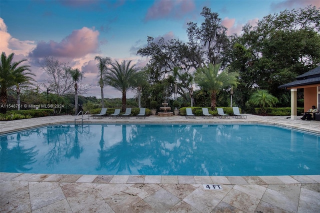 pool at dusk featuring a patio