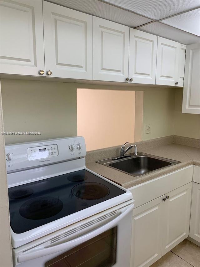 kitchen with white cabinets, white range with electric cooktop, sink, and light tile floors