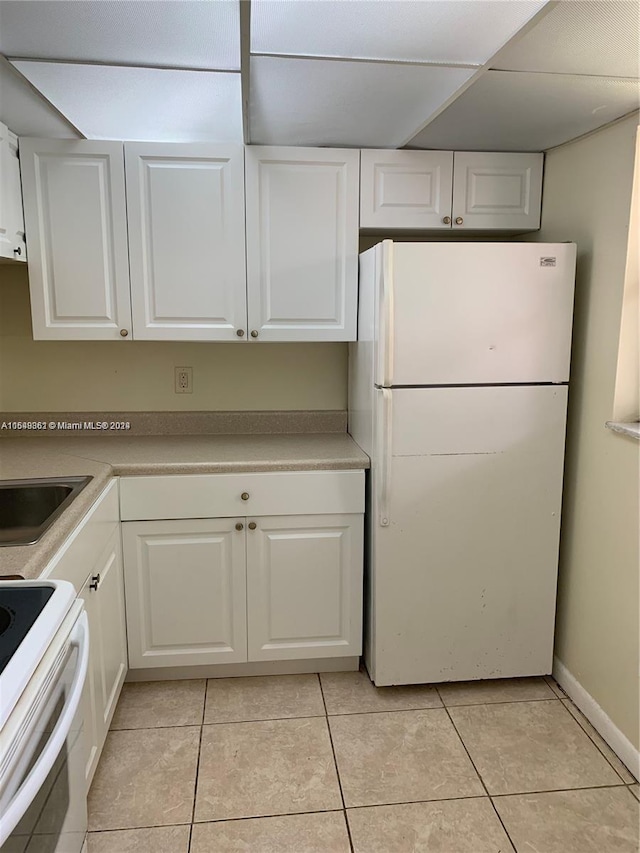 kitchen featuring white cabinets, white fridge, and light tile flooring