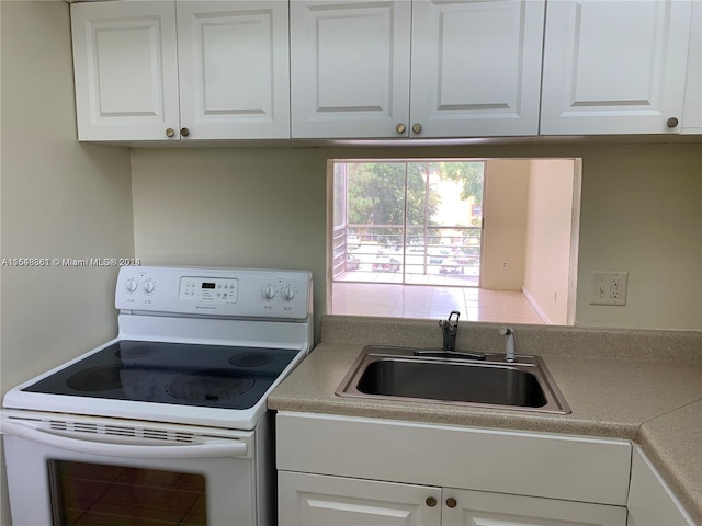 kitchen with white electric range, white cabinets, and sink