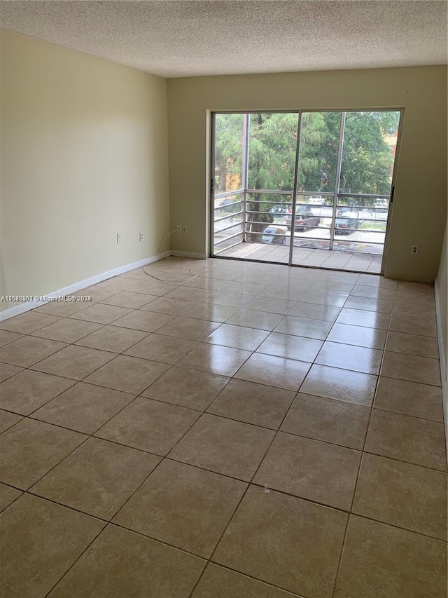 tiled empty room featuring a textured ceiling and a wealth of natural light