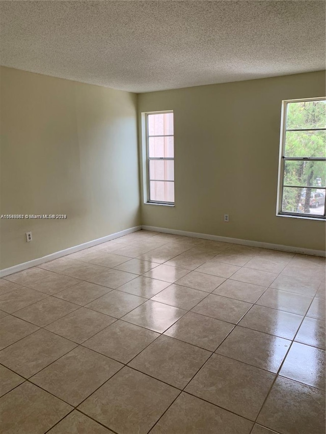 unfurnished room featuring a textured ceiling and light tile flooring