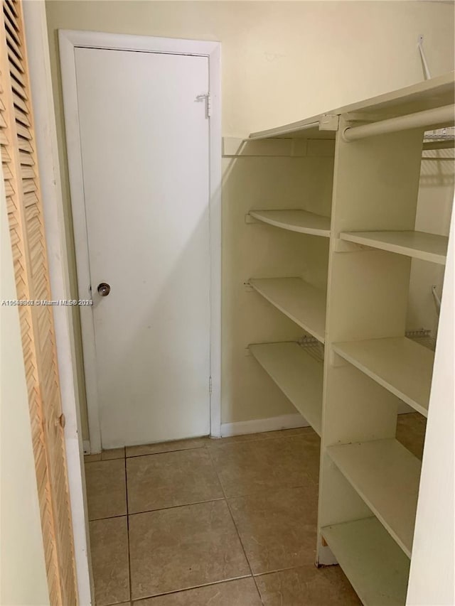 walk in closet featuring light tile floors