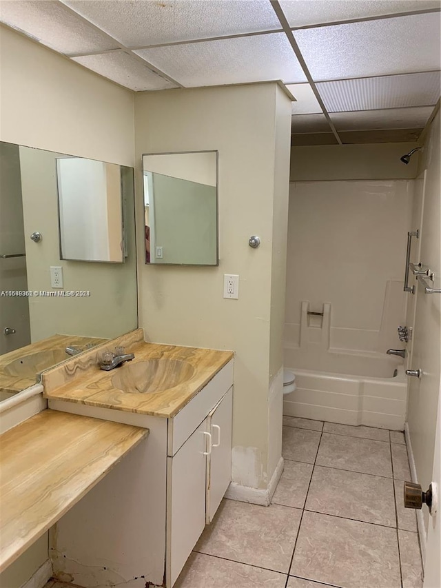 full bathroom featuring toilet, bathing tub / shower combination, a drop ceiling, tile flooring, and vanity