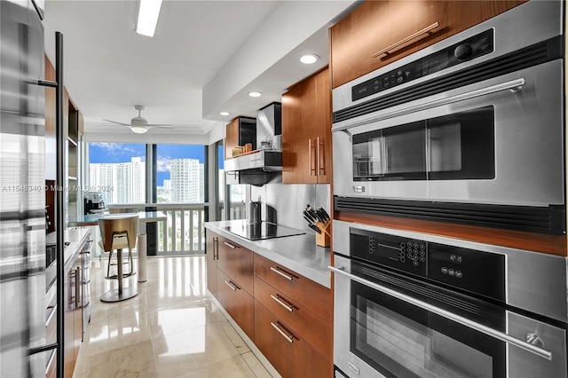 kitchen with black electric cooktop, light tile patterned floors, double oven, ceiling fan, and expansive windows