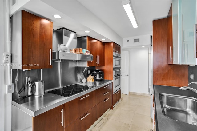 kitchen featuring black electric cooktop, wall chimney range hood, backsplash, light tile patterned floors, and stainless steel counters