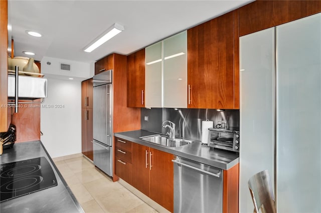 kitchen with appliances with stainless steel finishes, stainless steel counters, sink, backsplash, and light tile patterned flooring