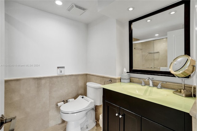 bathroom featuring vanity, tile walls, and toilet