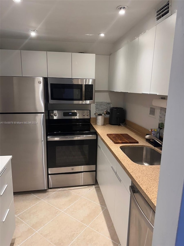 kitchen with white cabinets, light tile floors, appliances with stainless steel finishes, and sink