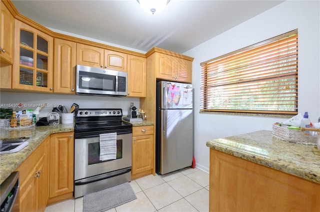 kitchen with light tile flooring, light stone countertops, and stainless steel appliances