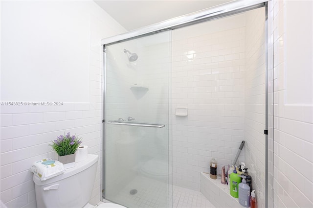 bathroom featuring toilet, walk in shower, and tile walls