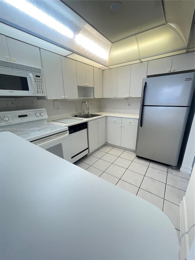 kitchen with white appliances, white cabinets, sink, and light tile flooring