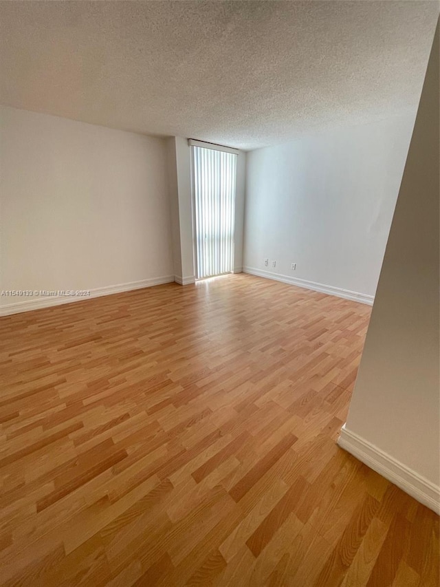 unfurnished room featuring a textured ceiling and light hardwood / wood-style flooring