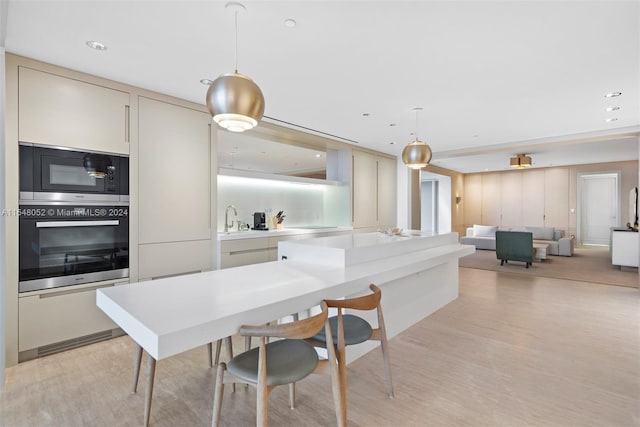 kitchen with light hardwood / wood-style floors, sink, stainless steel appliances, cream cabinets, and pendant lighting