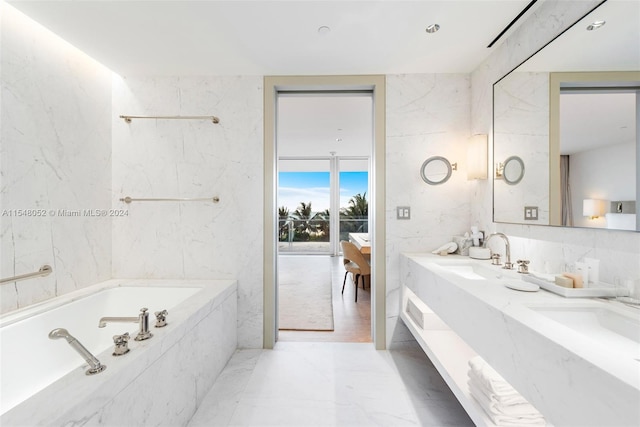 bathroom featuring tile walls, tiled bath, dual bowl vanity, and tile flooring