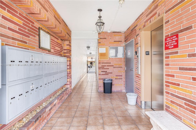 hall with brick wall, light tile flooring, and elevator