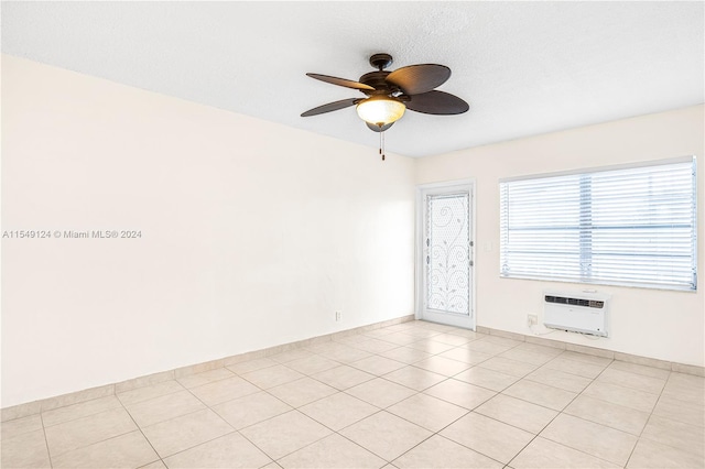 tiled empty room featuring an AC wall unit and ceiling fan