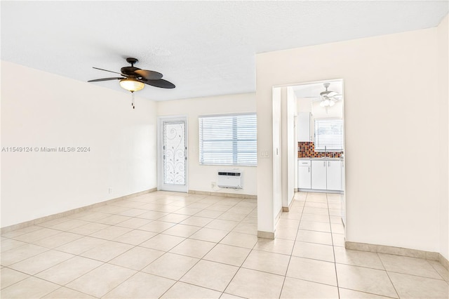 spare room featuring light tile floors, ceiling fan, sink, and a wall unit AC