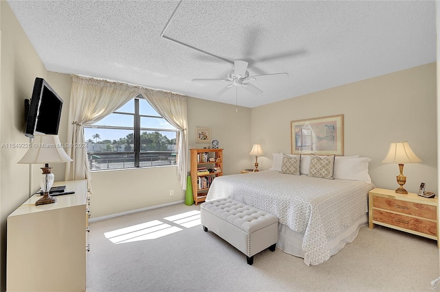 bedroom with light carpet, ceiling fan, and a textured ceiling