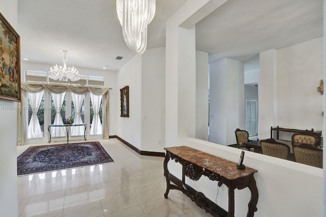 tiled foyer entrance with a textured ceiling and a chandelier