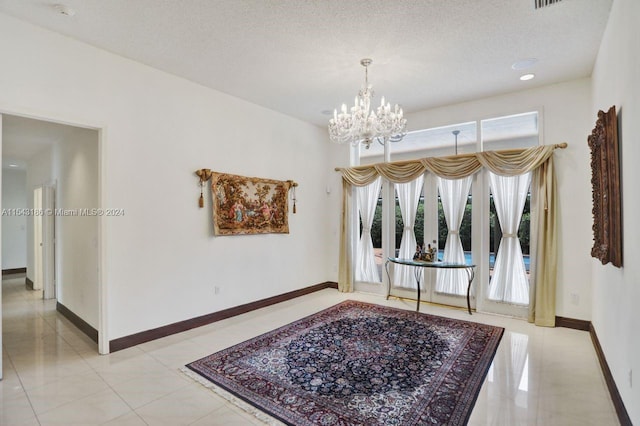 interior space featuring an inviting chandelier, a textured ceiling, and light tile patterned floors