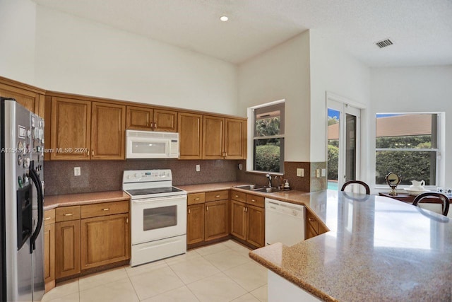 kitchen with decorative backsplash, a high ceiling, white appliances, and kitchen peninsula