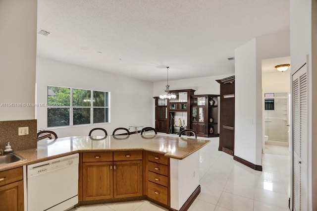 kitchen featuring kitchen peninsula, white dishwasher, decorative light fixtures, light tile patterned floors, and an inviting chandelier