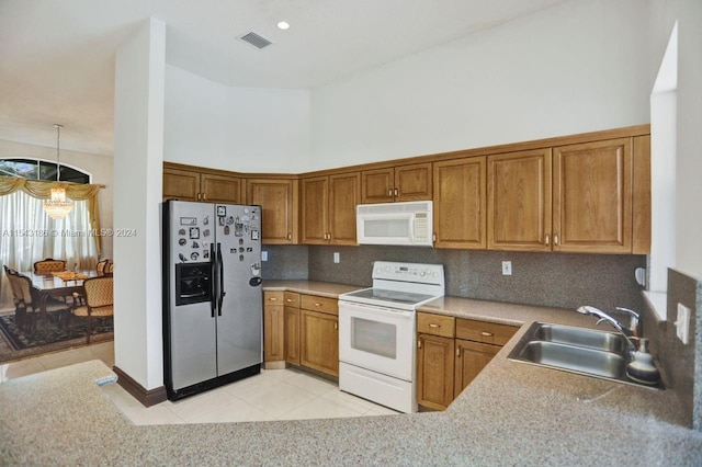 kitchen with white appliances, a towering ceiling, decorative light fixtures, sink, and light tile patterned flooring