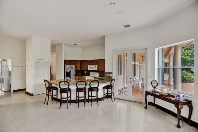 dining area featuring washer and clothes dryer, french doors, and light tile patterned flooring