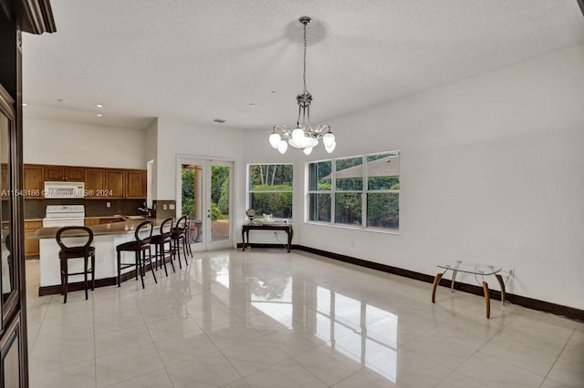 dining room with french doors, a textured ceiling, and a notable chandelier