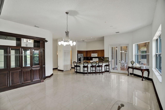 tiled dining space with a notable chandelier, french doors, plenty of natural light, and a textured ceiling