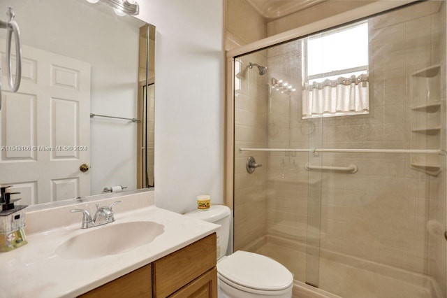 bathroom featuring toilet, a shower with door, and vanity