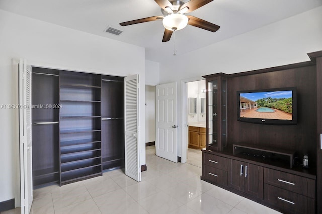 bedroom with ceiling fan, light tile patterned floors, a closet, and ensuite bathroom