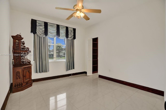 tiled empty room featuring ceiling fan