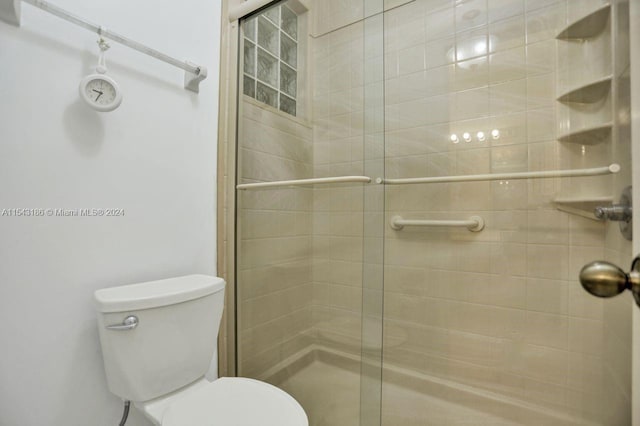 bathroom with toilet and a shower with door